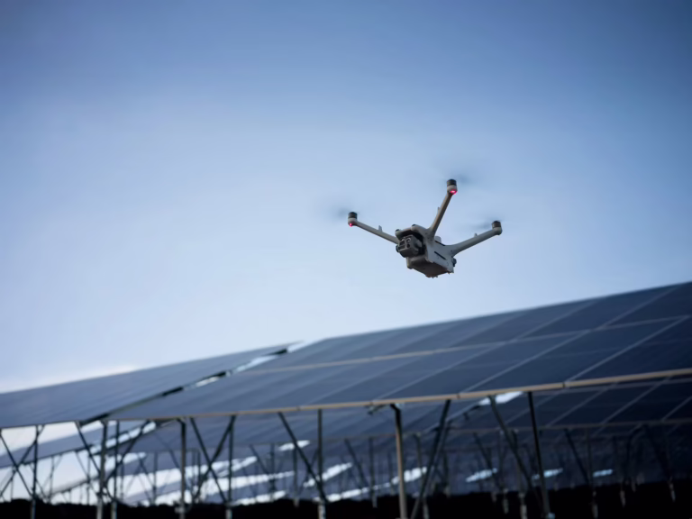 Camera drone flying above rows of solar panels